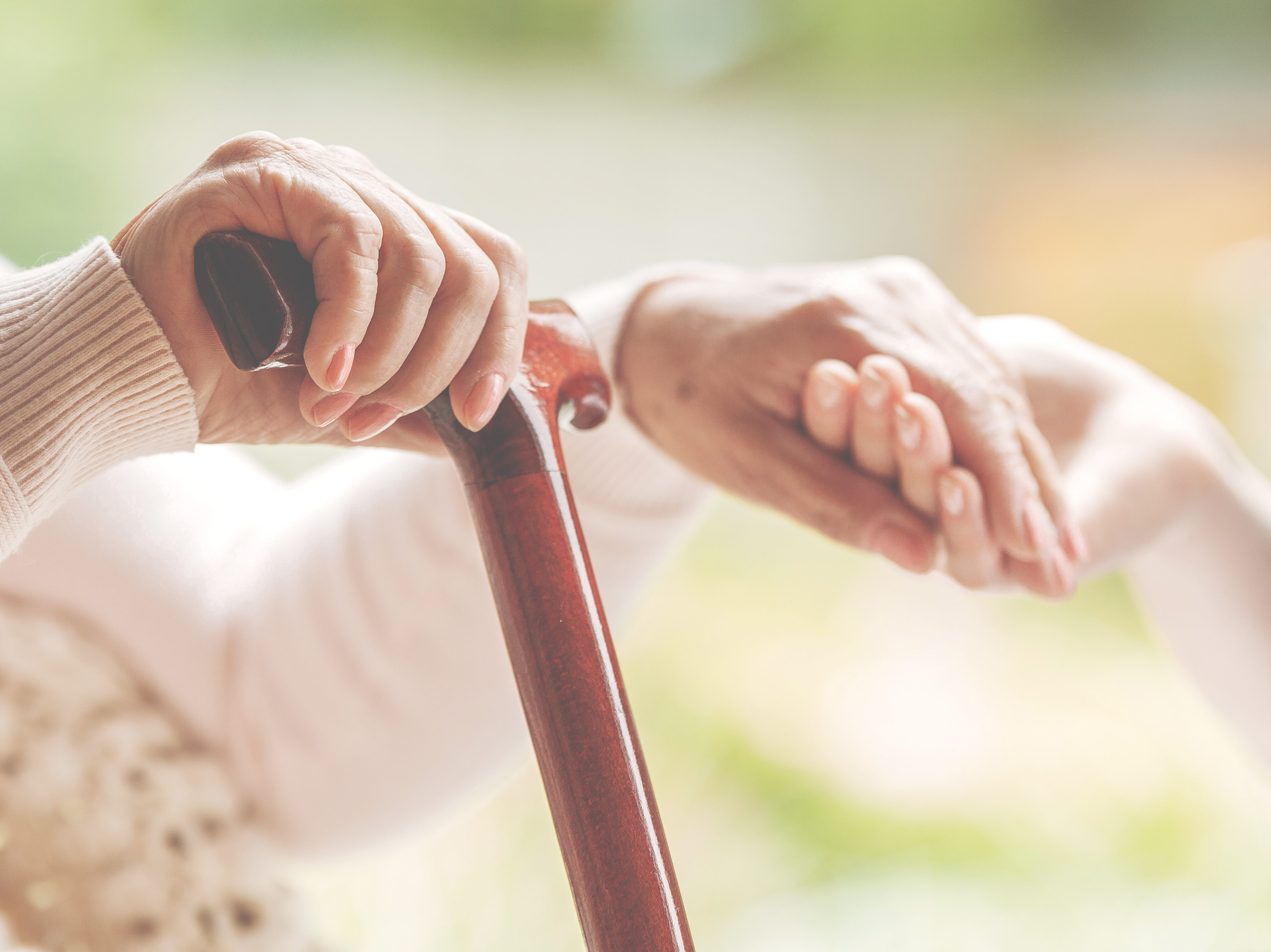 Closeup of senior lady holding walking stick in one hand and hol
